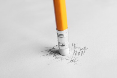 Erasing scribbles with graphite pencil on white background, closeup