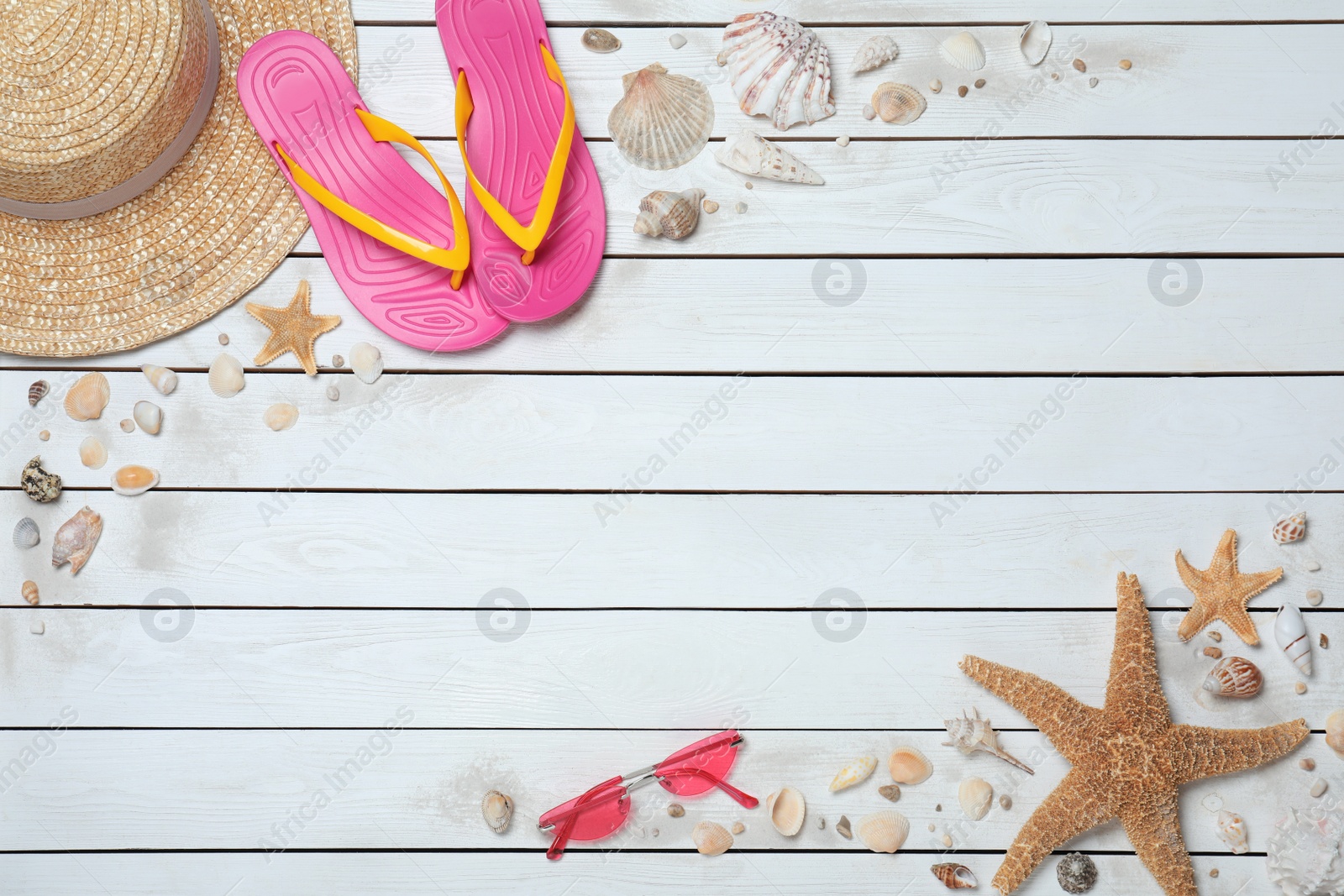 Photo of Stylish flip flops, sunglasses and hat on white wooden background, flat lay. Space for text