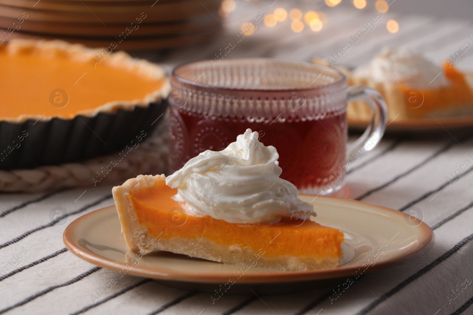 Photo of Piece of fresh homemade pumpkin pie served with whipped cream and tea on table