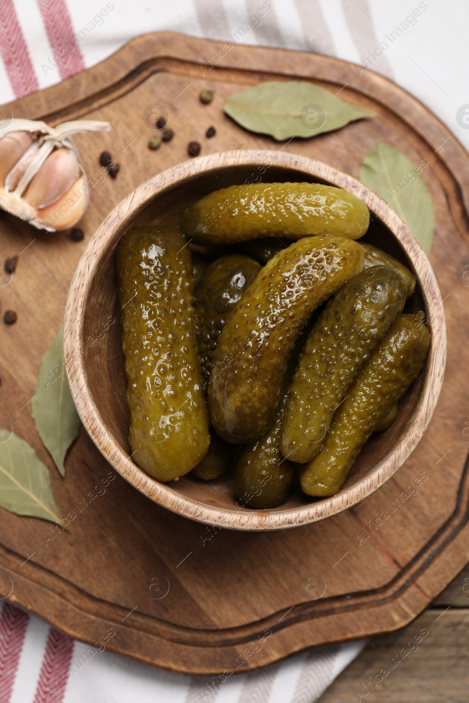 Photo of Tasty pickled cucumbers in bowl and spices on table, flat lay