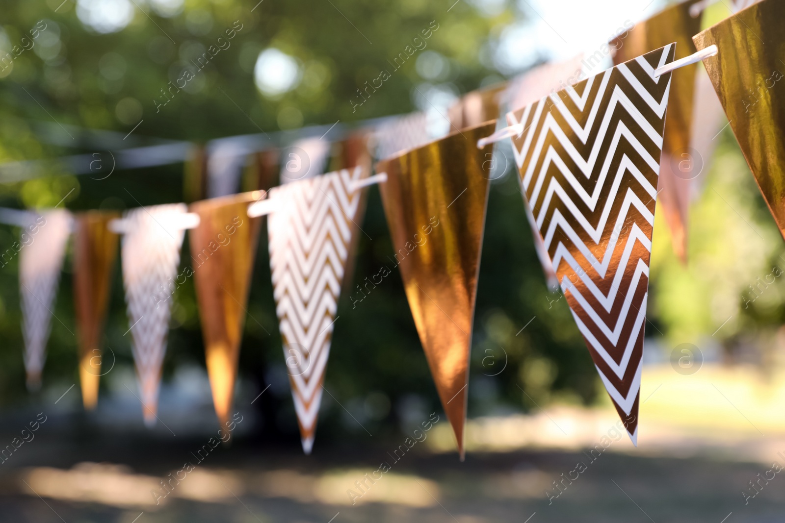 Photo of Golden bunting flags in park. Party decor