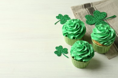 Photo of St. Patrick's day party. Tasty cupcakes with green cream on white table. Space for text