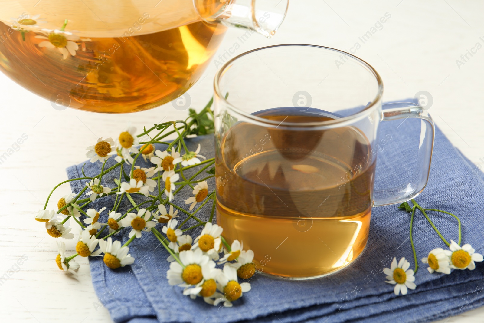 Photo of Pouring tasty chamomile tea into cup on table