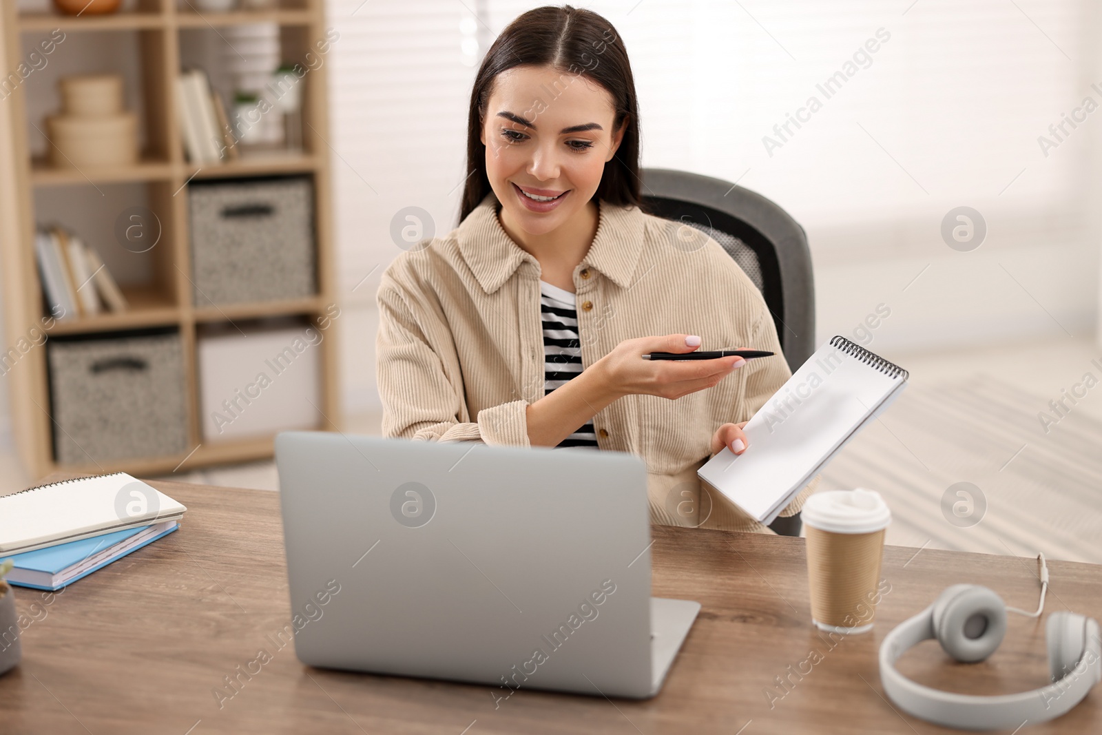 Photo of Young woman using video chat during webinar at table in room