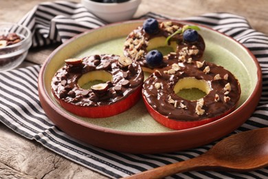 Photo of Fresh apples with nut butter, blueberries, hazelnuts and chocolate chips on table