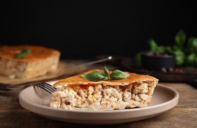 Piece of delicious pie with meat and basil on wooden table