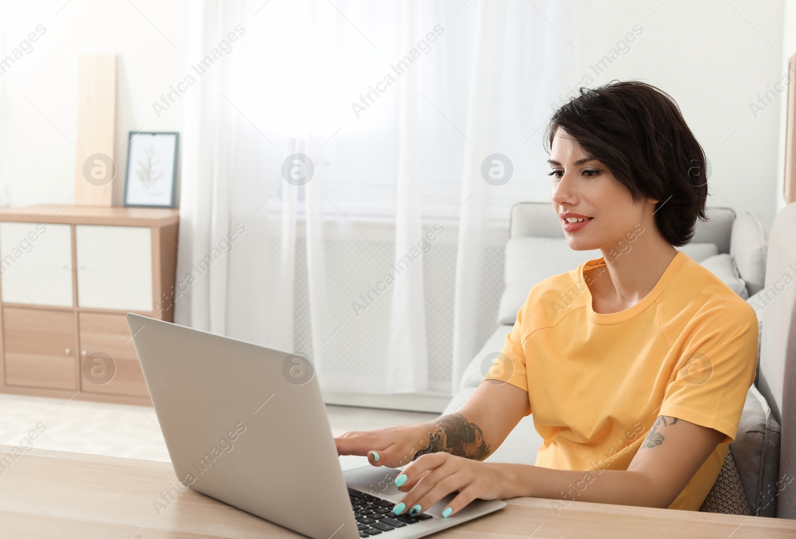 Photo of Young woman with modern laptop at desk in home office