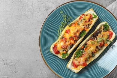 Plate of delicious stuffed zucchini on light grey table, top view. Space for text