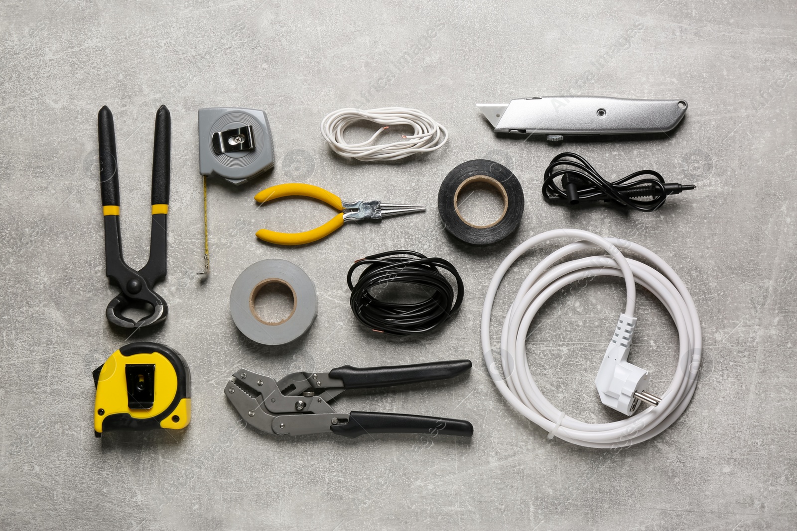 Photo of New wires and electrician's tools on grey table, flat lay