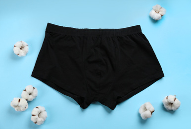 Photo of Black men's underwear and cotton flowers on light blue background, flat lay