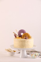 Photo of Delicious cake decorated with sweets, wafer rolls and marshmallows on white wooden table, space for text