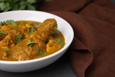 Photo of Delicious chicken with curry sauce on grey wooden table, closeup. Space for text