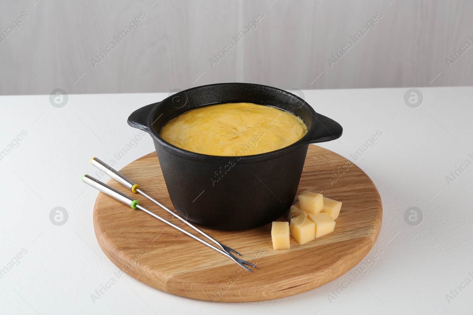 Photo of Fondue with tasty melted cheese and forks on white table