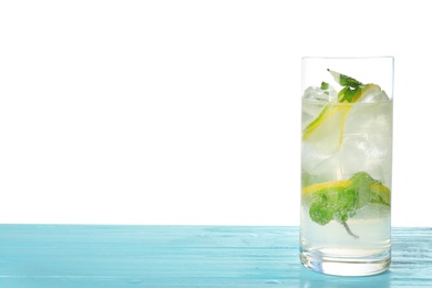 Photo of Glass of refreshing drink with citrus slices and mint on blue wooden table against white background