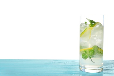 Glass of refreshing drink with citrus slices and mint on blue wooden table against white background