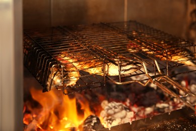 Photo of Grilling basket with whole fish in oven, closeup