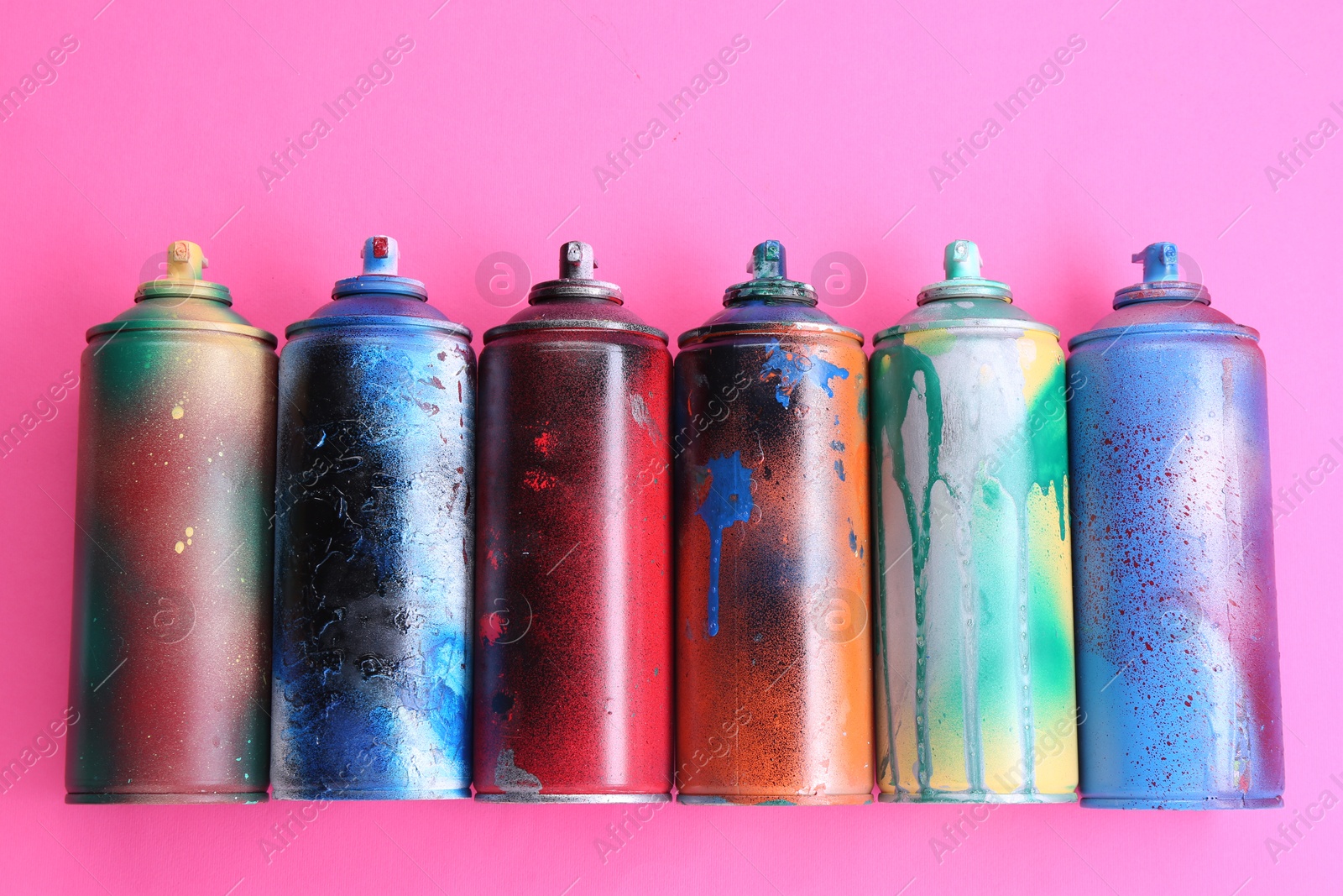 Photo of Many spray paint cans on pink background, flat lay