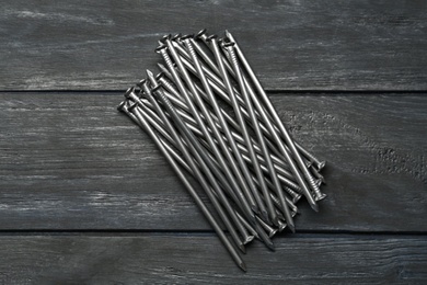 Photo of Pile of metal nails on grey wooden background, flat lay