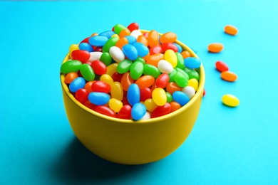 Photo of Bowl with colorful jelly beans on turquoise background
