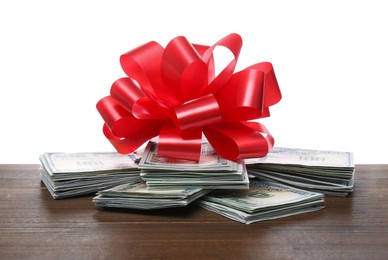 Photo of Dollar bills with red bow on wooden table against white background