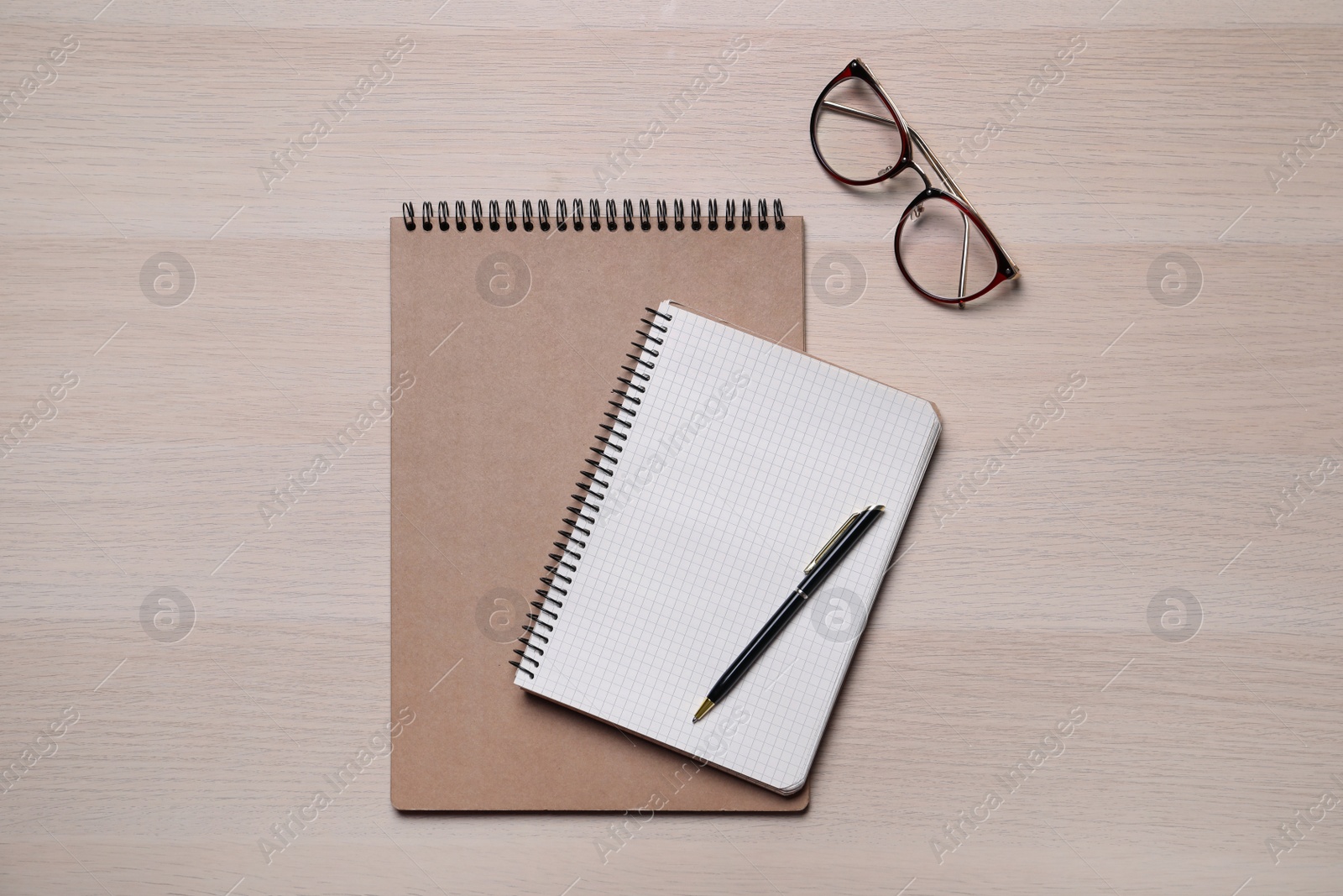 Photo of Notebooks, pen and glasses on wooden table, flat lay