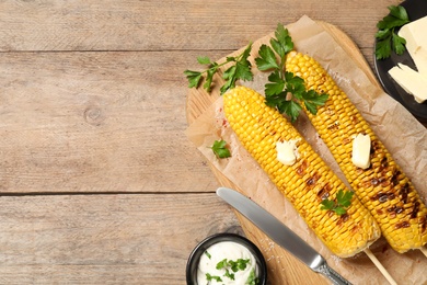 Photo of Tasty grilled corn on wooden table, flat lay. Space for text