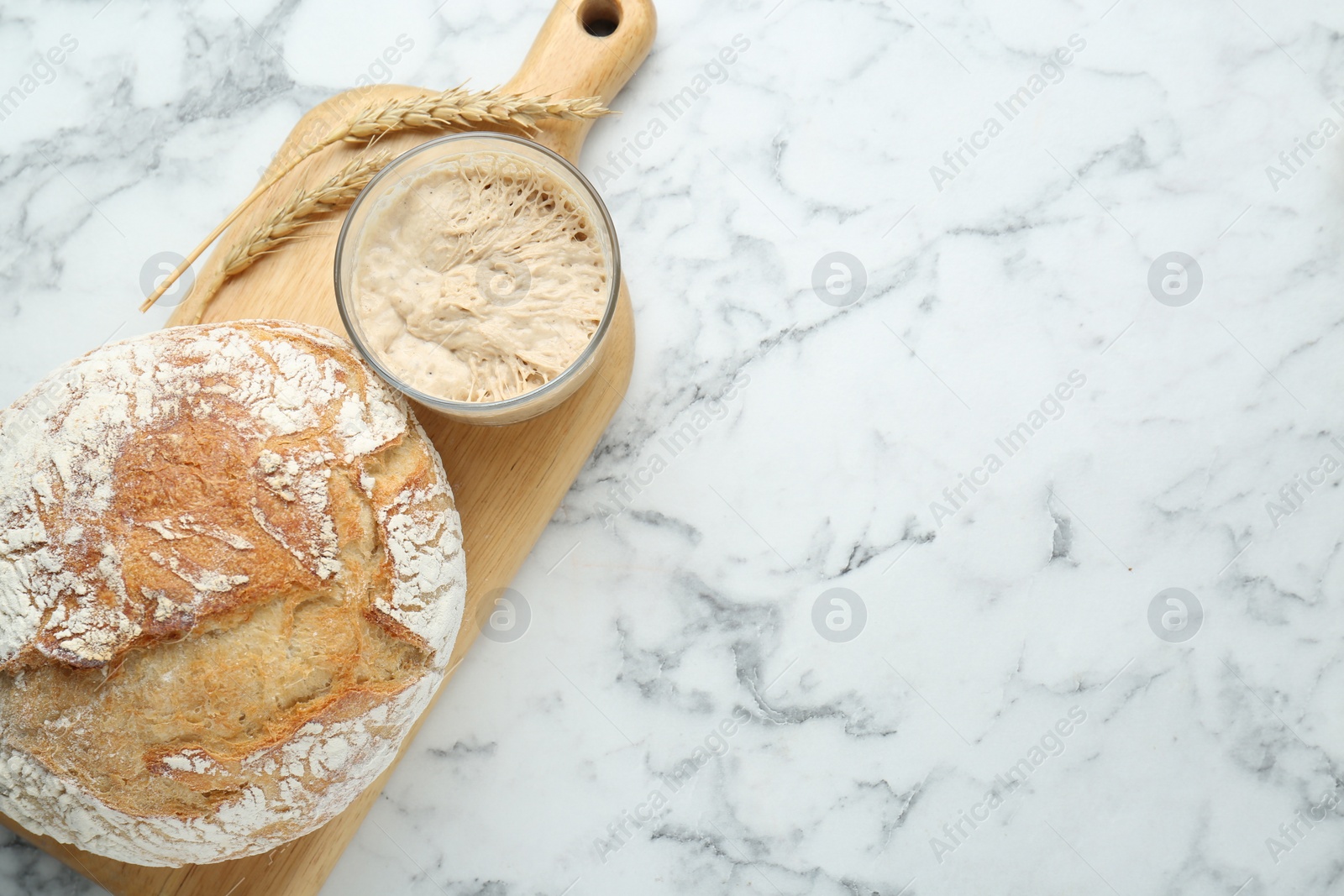 Photo of Freshly baked bread, spikes and sourdough on white marble table, top view. Space for text