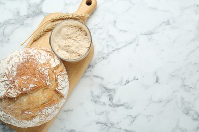 Photo of Freshly baked bread, spikes and sourdough on white marble table, top view. Space for text