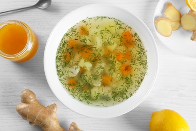 Flat lay composition with bowl of fresh homemade soup to cure flu on wooden background