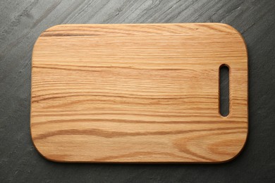 Photo of One wooden cutting board on dark grey table, top view