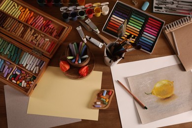Photo of Artist's workplace with drawing, soft pastels and color pencils on table, flat lay
