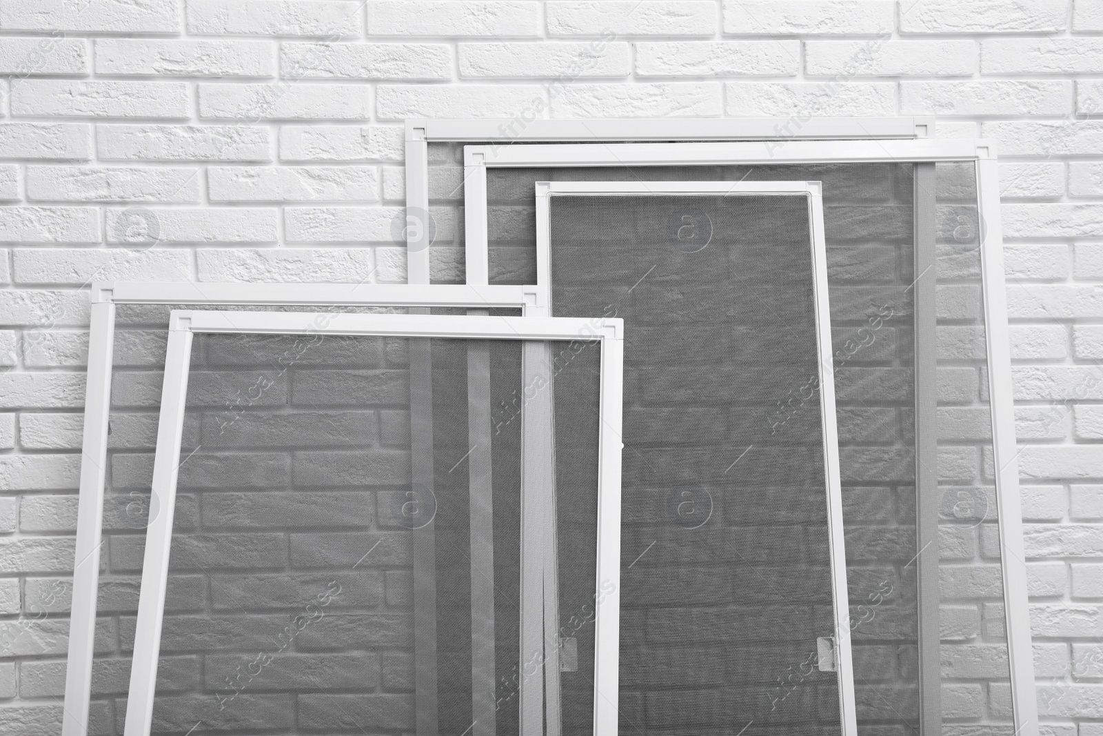 Photo of Set of window screens near white brick wall