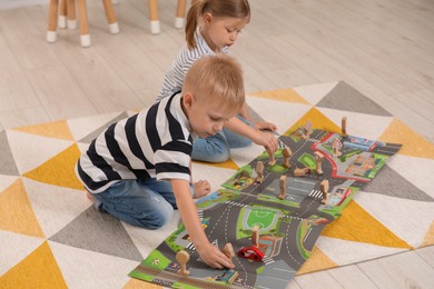 Photo of Little children playing with set of wooden road signs and toy cars indoors