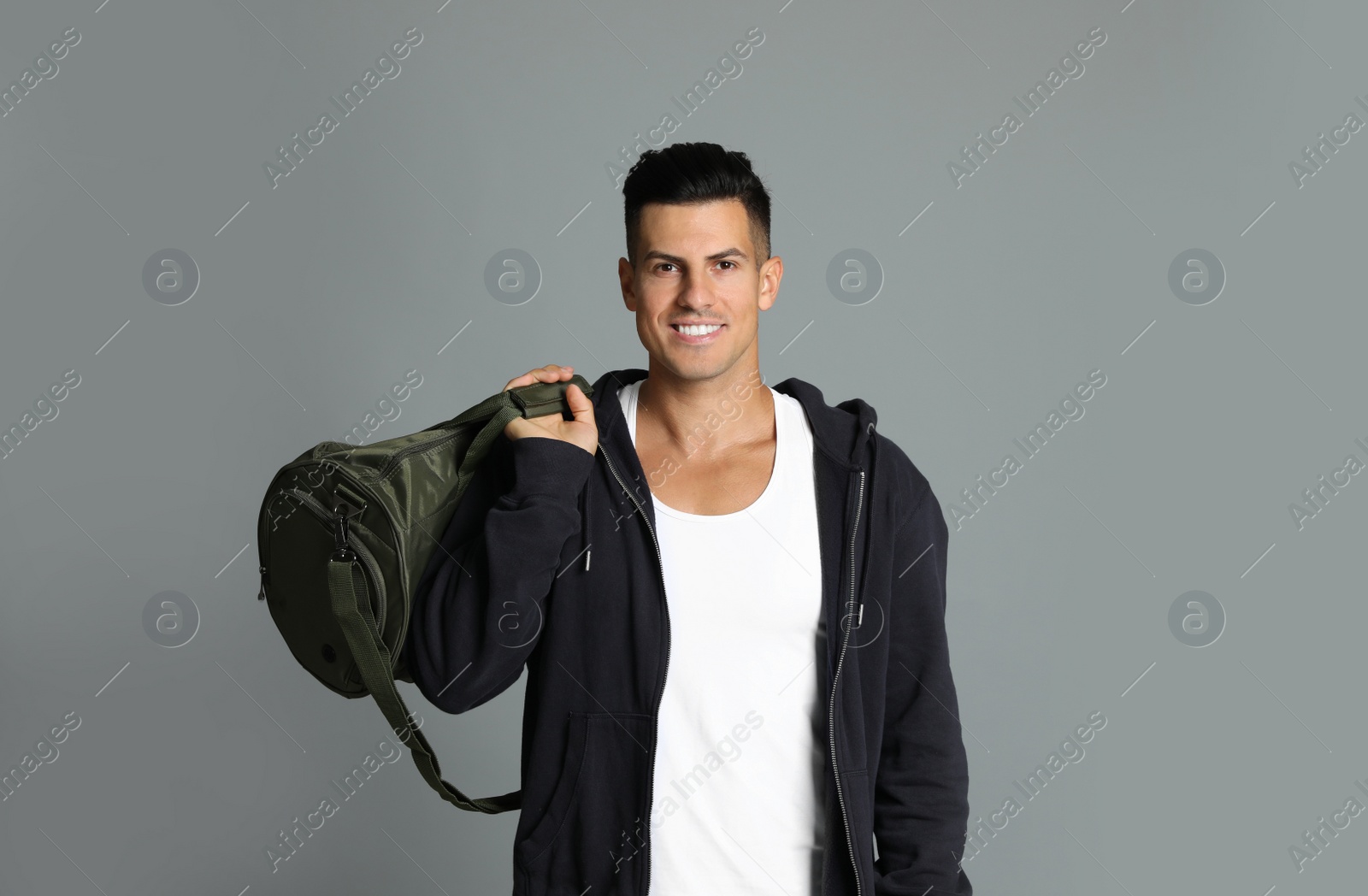 Photo of Handsome man with sports bag on grey background