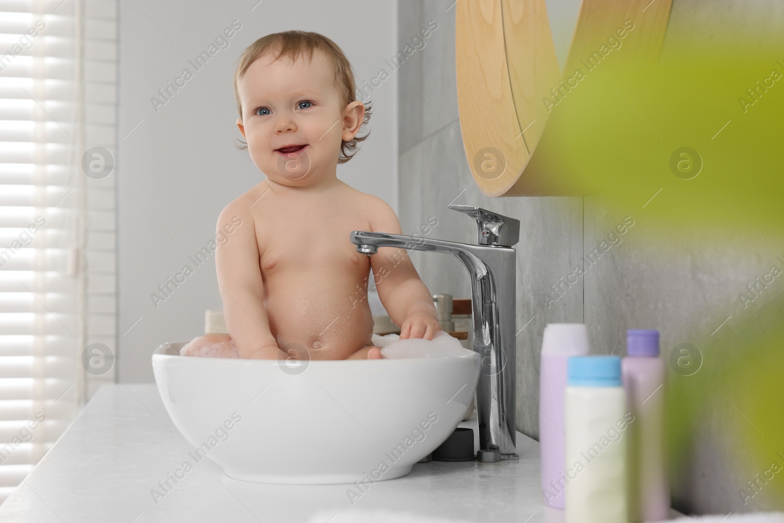 Photo of Cute little baby bathing in sink at home