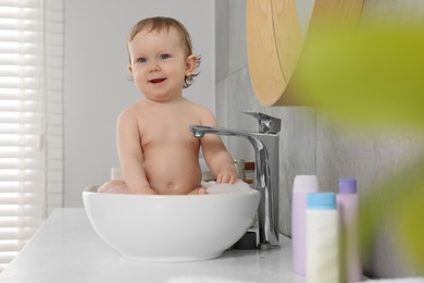 Cute little baby bathing in sink at home