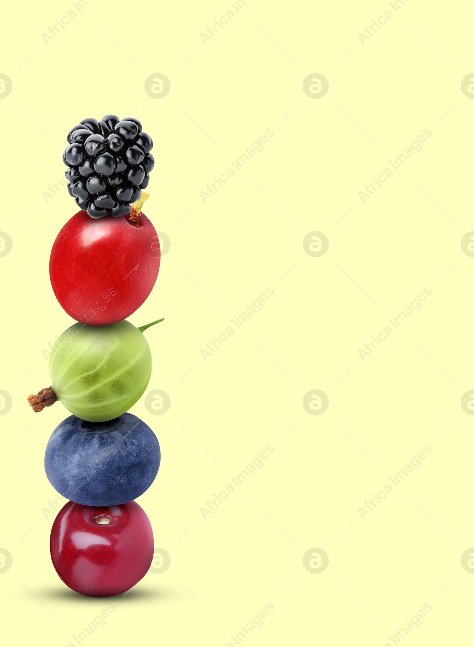 Image of Stack of different fresh tasty berries and cherry on honeydew color background, space for text