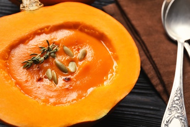 Photo of Tasty cream soup served in pumpkin on table, closeup