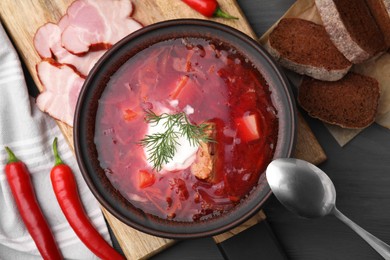 Photo of Tasty borscht with sour cream in bowl served on grey wooden table, flat lay