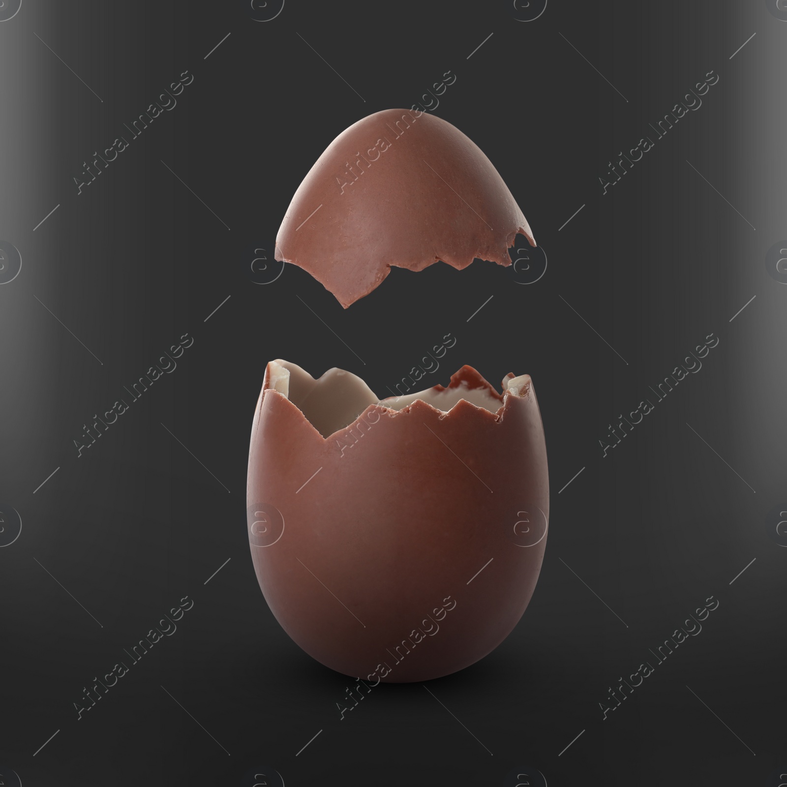 Image of Broken milk chocolate egg on black background