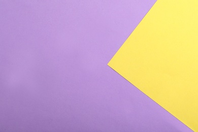 Violet and yellow paper sheets as colorful background, top view