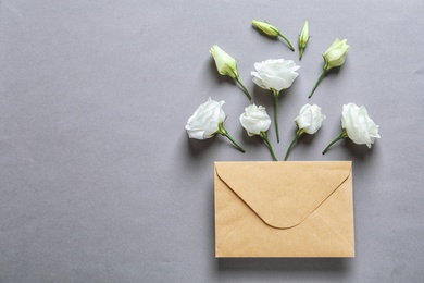 Photo of Beautiful Eustoma flowers and envelope on gray background