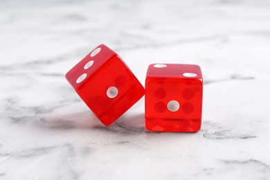 Photo of Two red game dices on white marble table, closeup