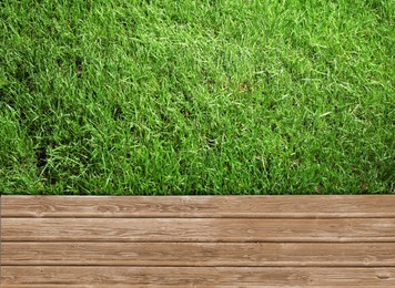 Image of Fresh green grass and wooden surface outdoors, top view
