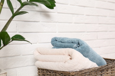 Photo of Basket with clean folded towels near brick wall