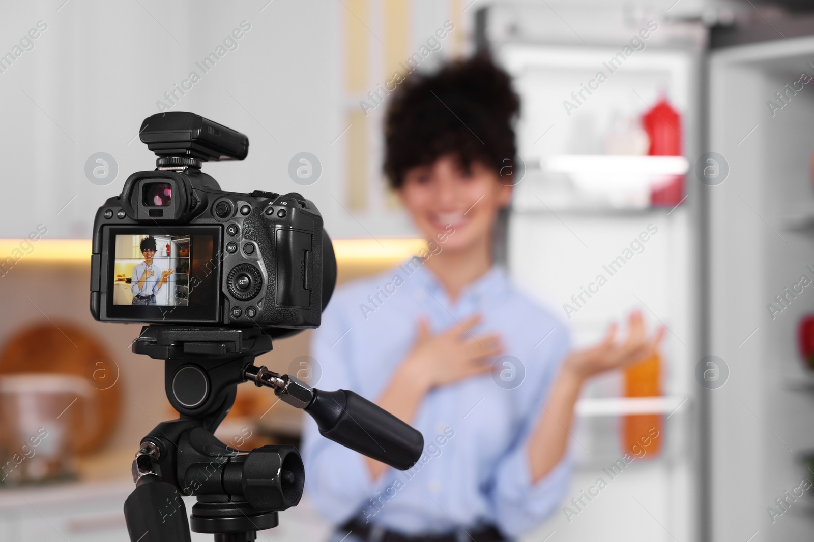 Photo of Food blogger recording video in kitchen, focus on camera