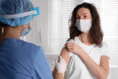 Photo of Doctor vaccinating mature woman against Covid-19 in clinic