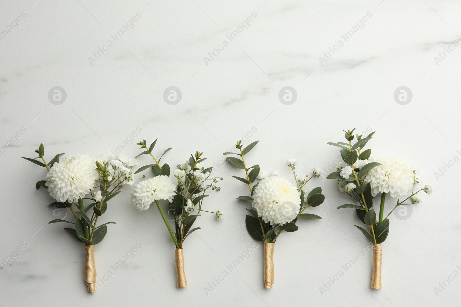 Photo of Small stylish boutonnieres on white marble table, flat lay. Space for text