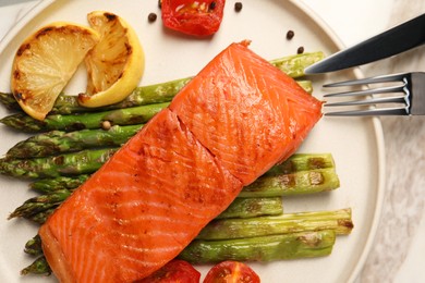 Photo of Tasty grilled salmon with asparagus, tomatoes, lemon and spices served on table, top view