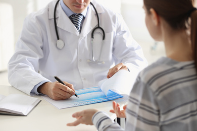 Photo of Doctor consulting patient at desk in clinic, closeup